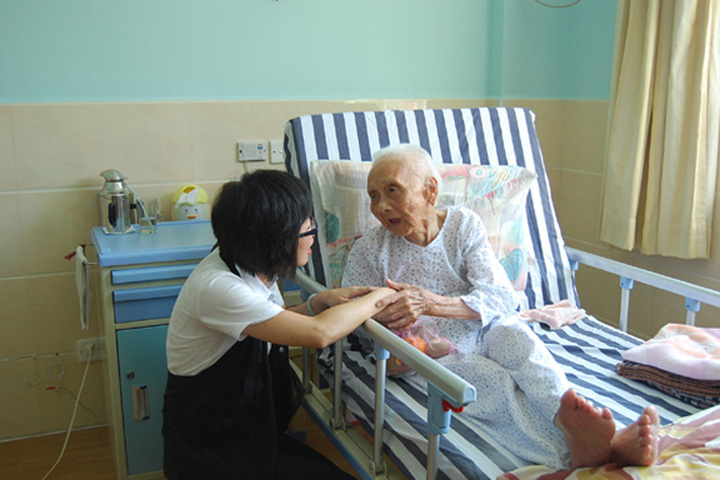 A YICT employee presents gifts to a senior and says Happy Festival and Good Health.